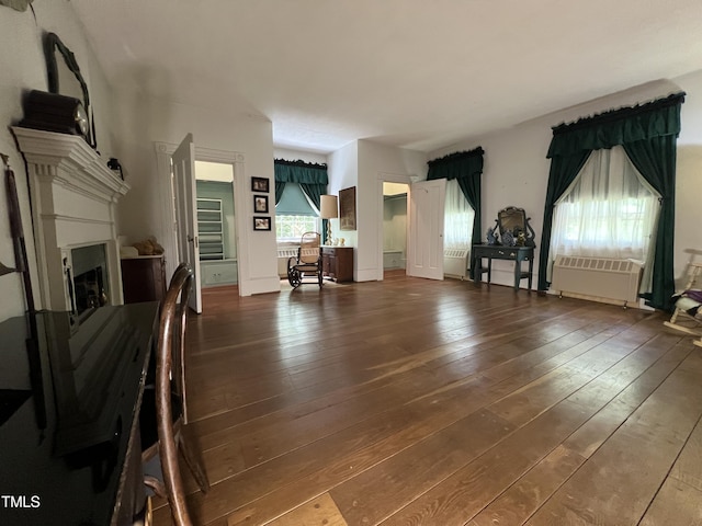 unfurnished living room with radiator, a fireplace, and dark wood-style floors