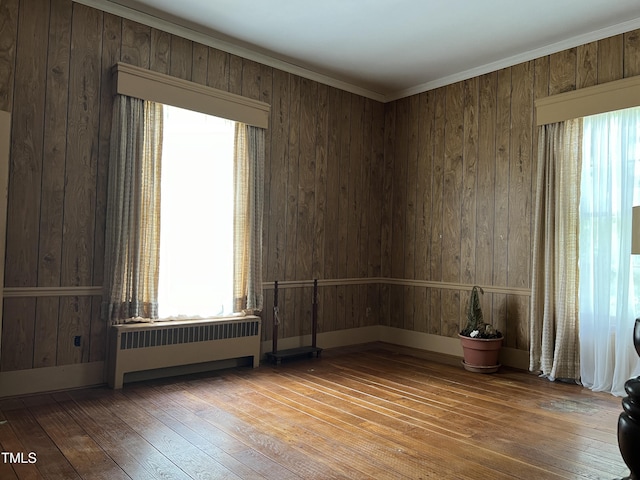 unfurnished room featuring wood-type flooring, radiator heating unit, and plenty of natural light