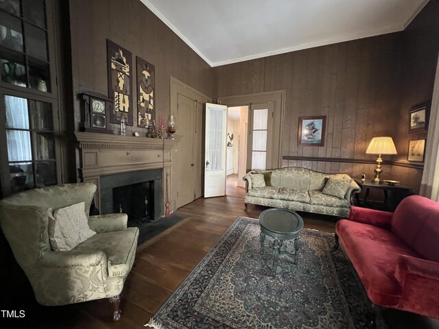 living area featuring a fireplace with flush hearth, wood finished floors, wood walls, and ornamental molding