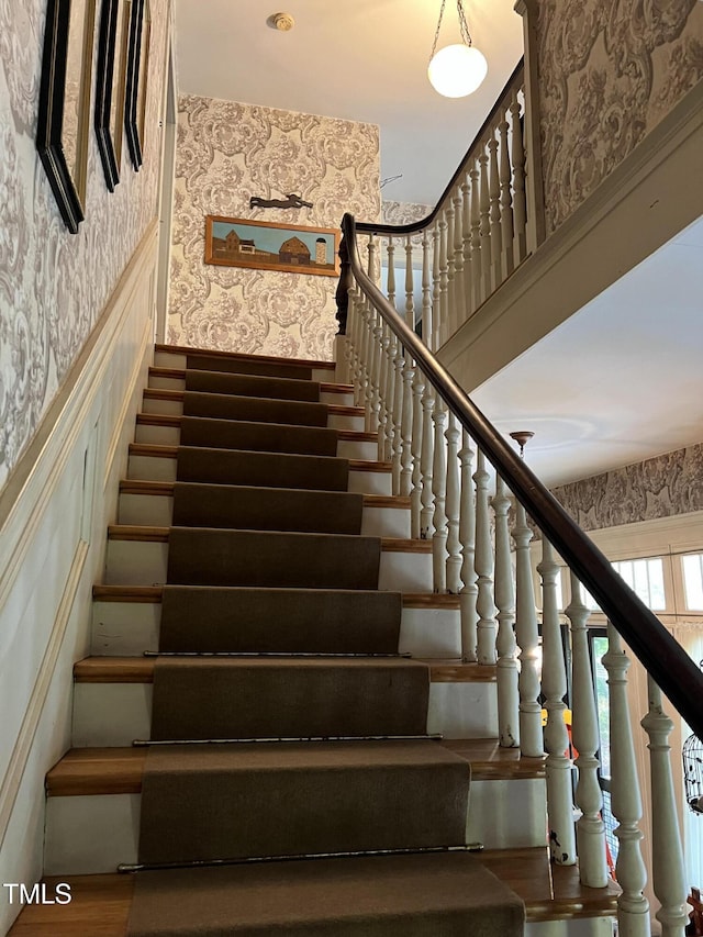 stairs with wallpapered walls and wainscoting