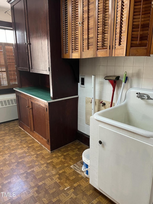 laundry room featuring radiator heating unit and cabinet space