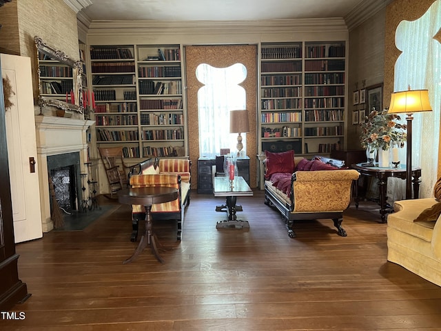 living area featuring a fireplace with flush hearth, built in features, ornamental molding, and wood-type flooring