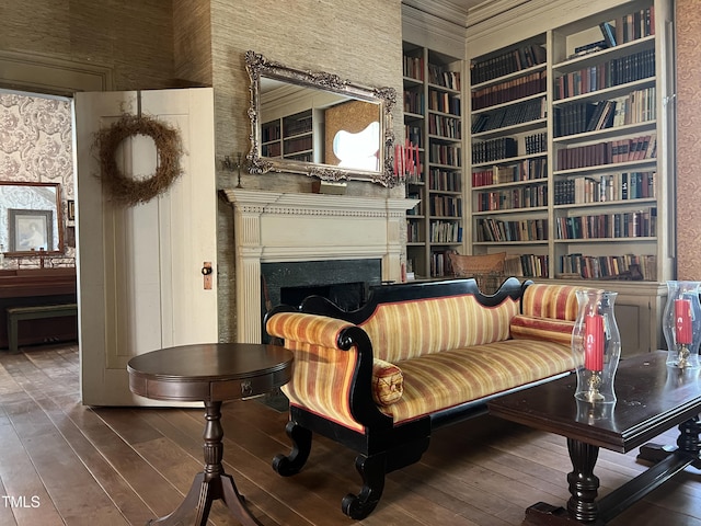 living area featuring hardwood / wood-style flooring, built in features, a fireplace, and crown molding