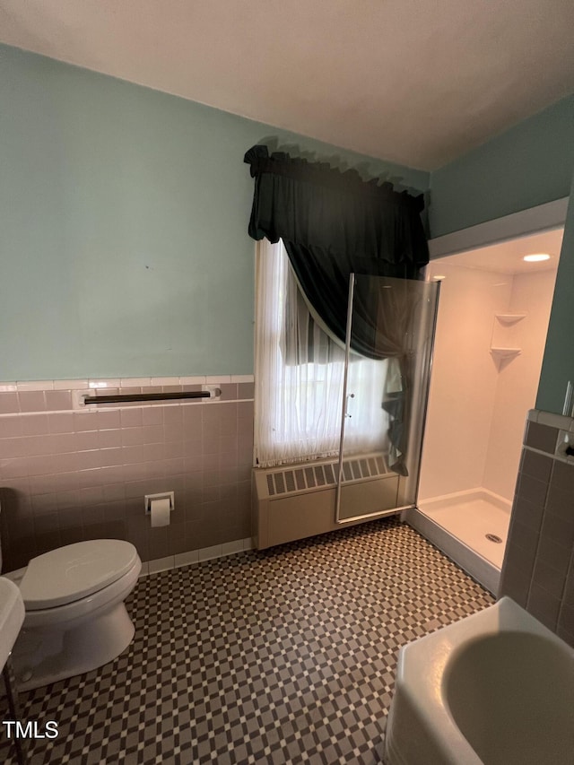 full bath with tile patterned floors, toilet, a walk in shower, tile walls, and wainscoting