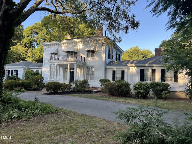 view of front of home featuring a chimney and a balcony