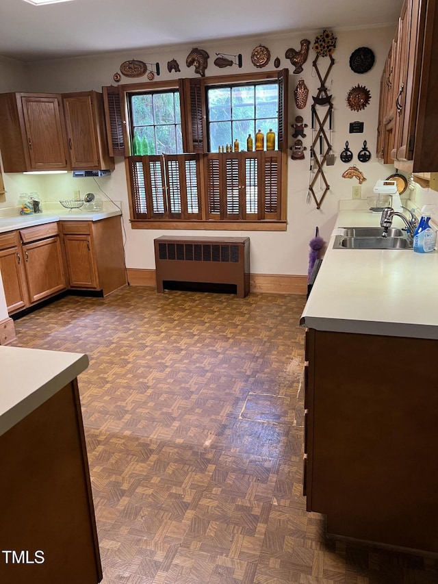 kitchen featuring radiator, light countertops, baseboards, and a sink