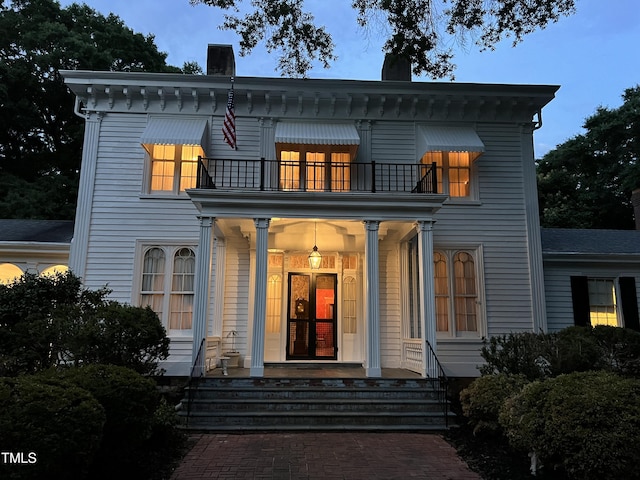 view of front of property with a chimney, a balcony, and covered porch