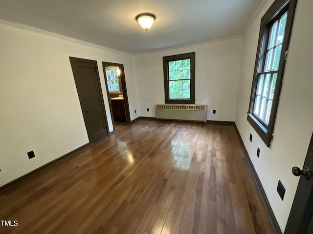 spare room featuring radiator heating unit, baseboards, dark wood-style floors, and ornamental molding