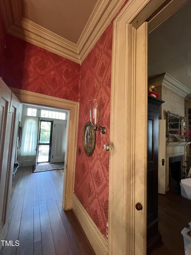 hallway featuring wallpapered walls, hardwood / wood-style floors, and ornamental molding