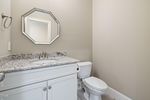 bathroom with vanity, toilet, and baseboards