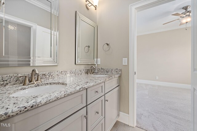 full bathroom featuring a ceiling fan, baseboards, double vanity, and ornamental molding