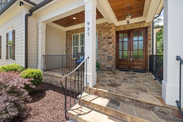 entrance to property with covered porch, french doors, and stone siding