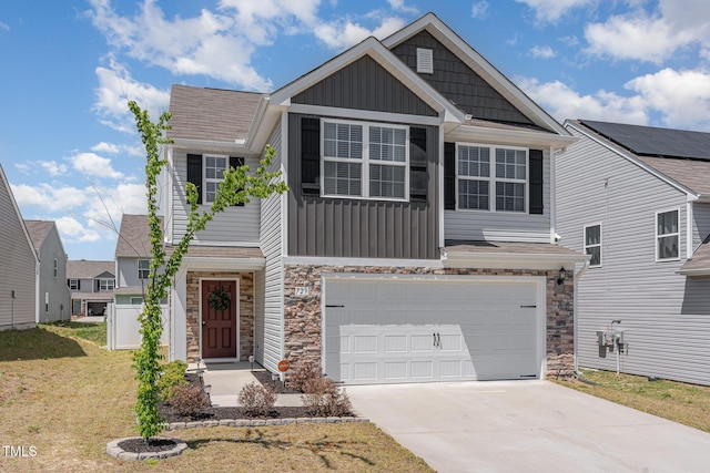 craftsman inspired home with board and batten siding, a front yard, stone siding, and concrete driveway