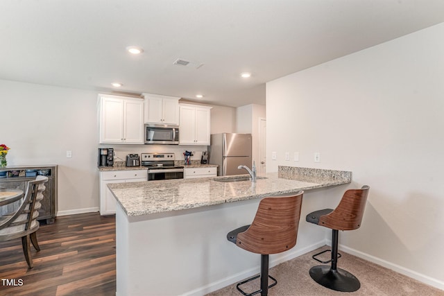 kitchen featuring white cabinets, appliances with stainless steel finishes, a breakfast bar area, a peninsula, and visible vents