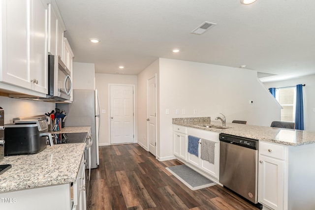 kitchen with dark wood-style flooring, a sink, white cabinets, a peninsula, and stainless steel appliances