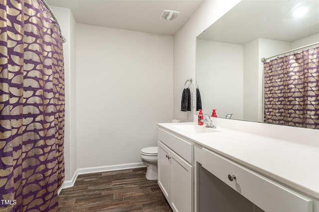 bathroom featuring vanity, toilet, baseboards, wood finished floors, and visible vents