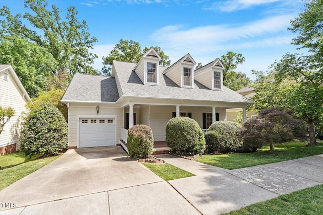 cape cod home featuring a porch, driveway, a front yard, roof with shingles, and an attached garage