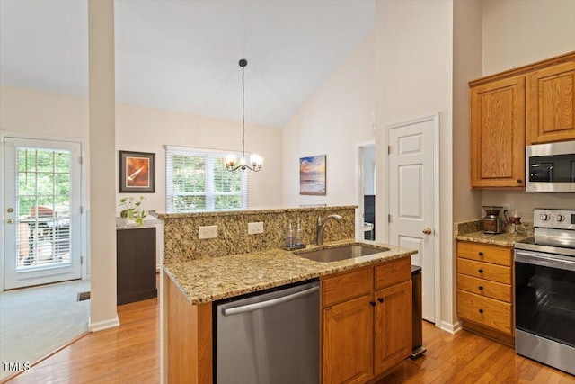 kitchen featuring a sink, appliances with stainless steel finishes, light wood-style floors, and a wealth of natural light