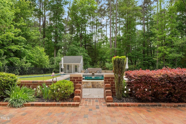 view of patio with an outdoor structure, an outdoor pool, a storage structure, and fence