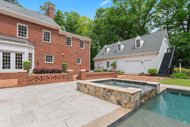 pool with stairs, a patio area, and an in ground hot tub
