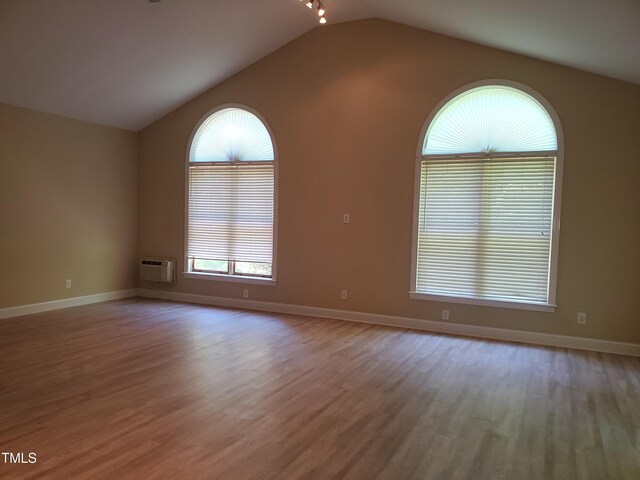 725 Van Thomas Dr, Raleigh, NC 27615 - unfurnished room with vaulted ceiling, wood finished floors, a wall mounted AC, and baseboards