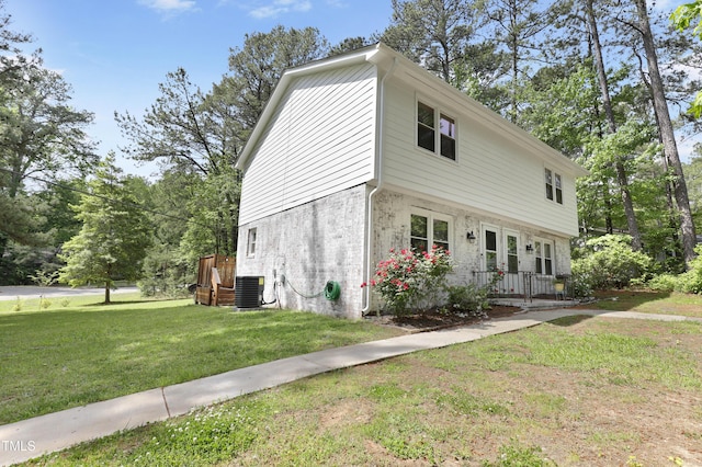 view of property exterior featuring a lawn, central air condition unit, and brick siding