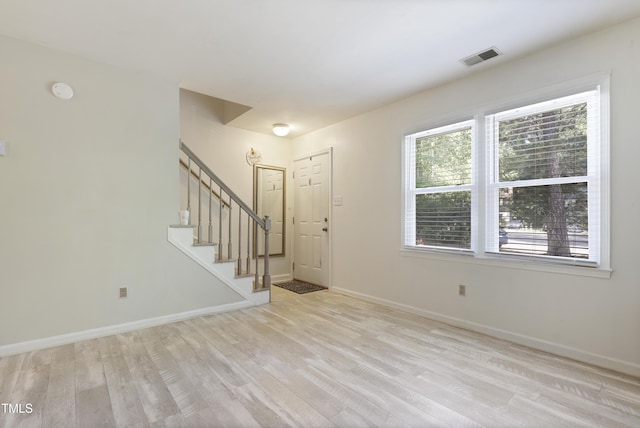 foyer entrance featuring light wood-type flooring, stairs, a healthy amount of sunlight, and visible vents