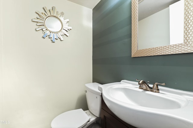half bath featuring vanity and toilet