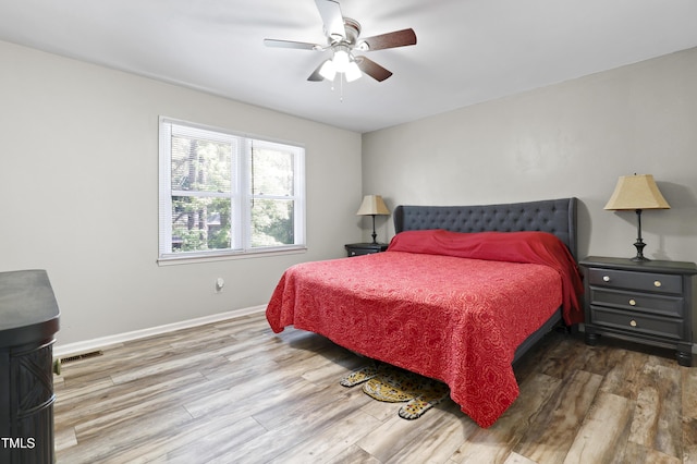 bedroom featuring ceiling fan, baseboards, visible vents, and wood finished floors