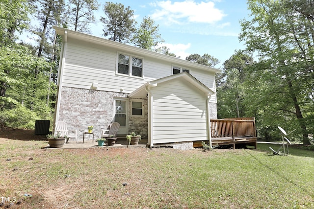 rear view of house featuring brick siding, a yard, and a deck