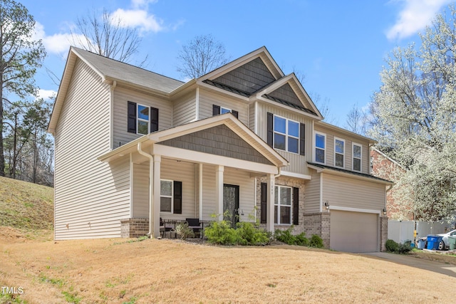 craftsman house featuring driveway, brick siding, a porch, a front lawn, and a garage