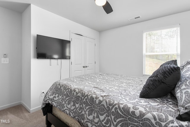 carpeted bedroom with visible vents, baseboards, a ceiling fan, and a closet