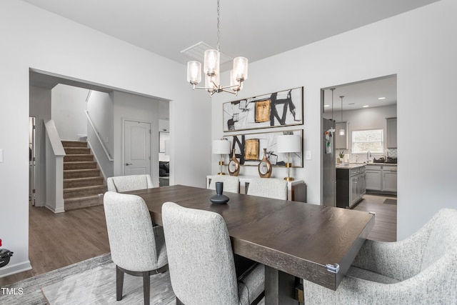 dining area with a notable chandelier, stairway, and light wood-style floors