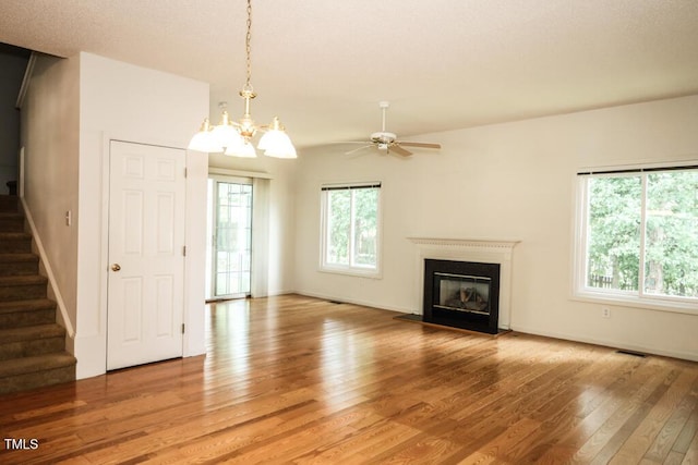 2528 Beech Gap Ct, Raleigh, NC 27603 - unfurnished living room featuring light wood finished floors, stairway, a fireplace with flush hearth, a ceiling fan, and a chandelier
