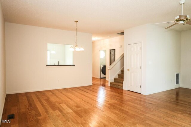 2528 Beech Gap Ct, Raleigh, NC 27603 - unfurnished living room featuring washer / dryer, a chandelier, light wood-type flooring, stairway, and ceiling fan