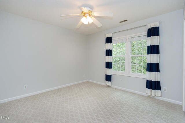 carpeted spare room with baseboards, visible vents, and ceiling fan
