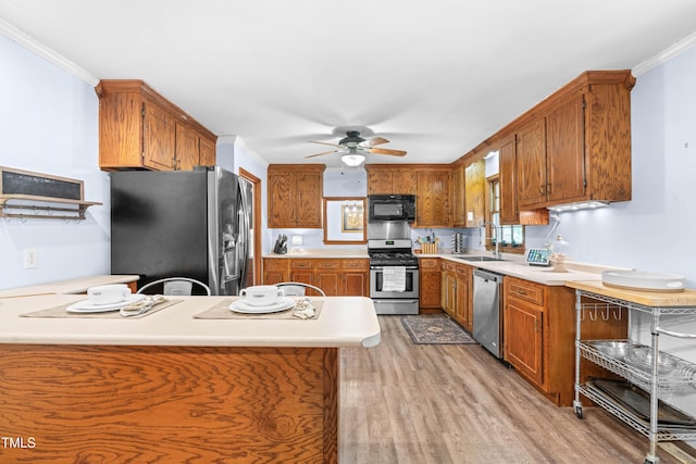 149 Baldwin Dr, Durham, NC 27712 - kitchen featuring brown cabinets, light wood-style flooring, a sink, stainless steel appliances, and a ceiling fan