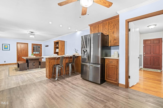 149 Baldwin Dr, Durham, NC 27712 - kitchen featuring a breakfast bar, brown cabinetry, stainless steel refrigerator with ice dispenser, and light wood-style floors