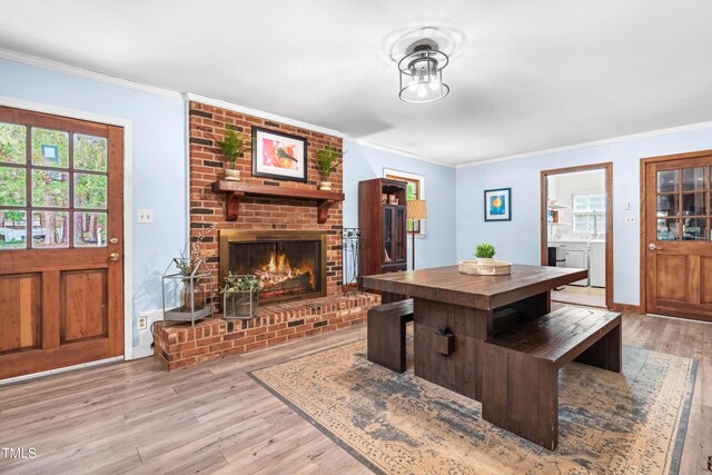 149 Baldwin Dr, Durham, NC 27712 - living area with washing machine and dryer, light wood-style floors, baseboards, ornamental molding, and a brick fireplace