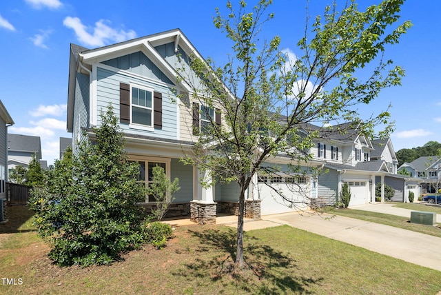 craftsman-style house with a front yard, driveway, stone siding, board and batten siding, and an attached garage