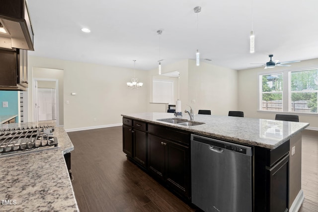 kitchen with a sink, stainless steel appliances, baseboards, light stone countertops, and dark wood finished floors