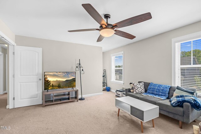 carpeted living area with baseboards and ceiling fan