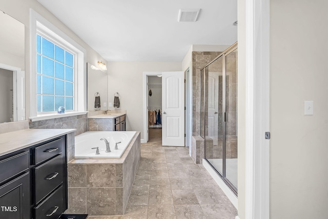 bathroom featuring a shower stall, a bath, vanity, a walk in closet, and visible vents