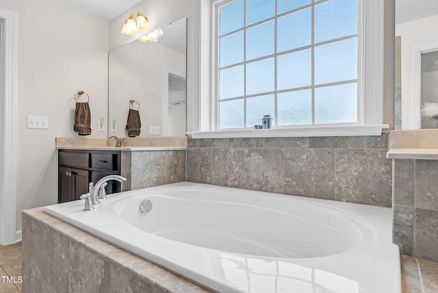 full bath with a garden tub, vanity, and baseboards