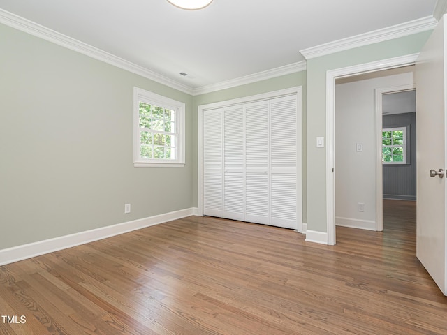 3009 Hillmer Dr, Raleigh, NC 27609 - unfurnished bedroom with a closet, baseboards, multiple windows, crown molding, and wood finished floors