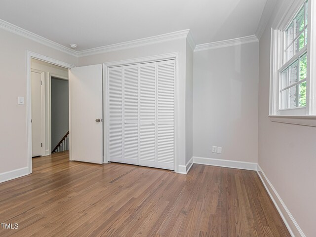 3009 Hillmer Dr, Raleigh, NC 27609 - unfurnished bedroom with ornamental molding, a closet, baseboards, and wood finished floors