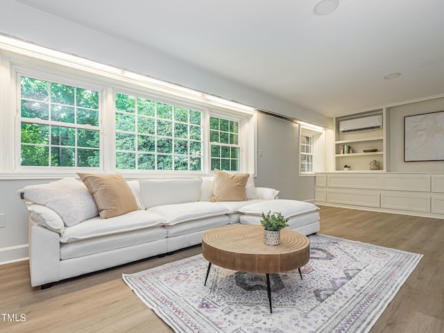 3009 Hillmer Dr, Raleigh, NC 27609 - living room featuring wood finished floors, baseboards, a healthy amount of sunlight, and an AC wall unit