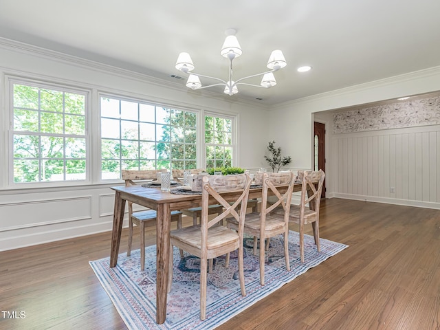3009 Hillmer Dr, Raleigh, NC 27609 - dining area featuring an inviting chandelier, wainscoting, a decorative wall, crown molding, and wood finished floors