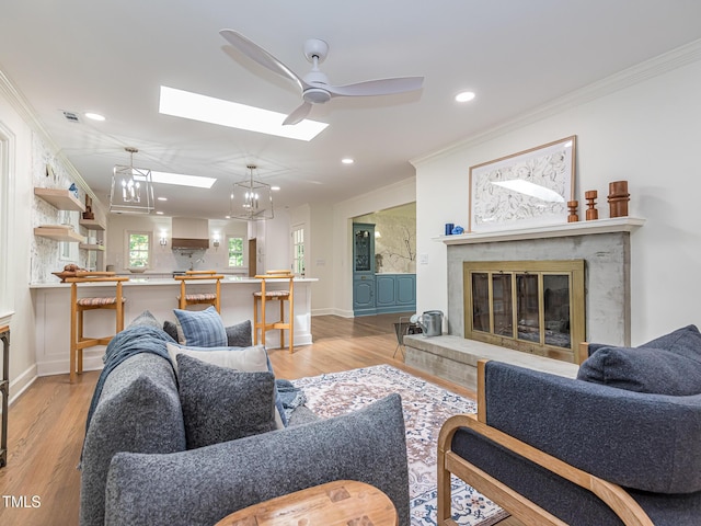 3009 Hillmer Dr, Raleigh, NC 27609 - living area with ornamental molding, a fireplace, ceiling fan, and a skylight