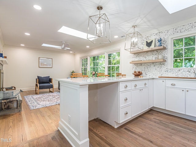 3009 Hillmer Dr, Raleigh, NC 27609 - kitchen featuring ornamental molding, a healthy amount of sunlight, light wood-style flooring, and a skylight